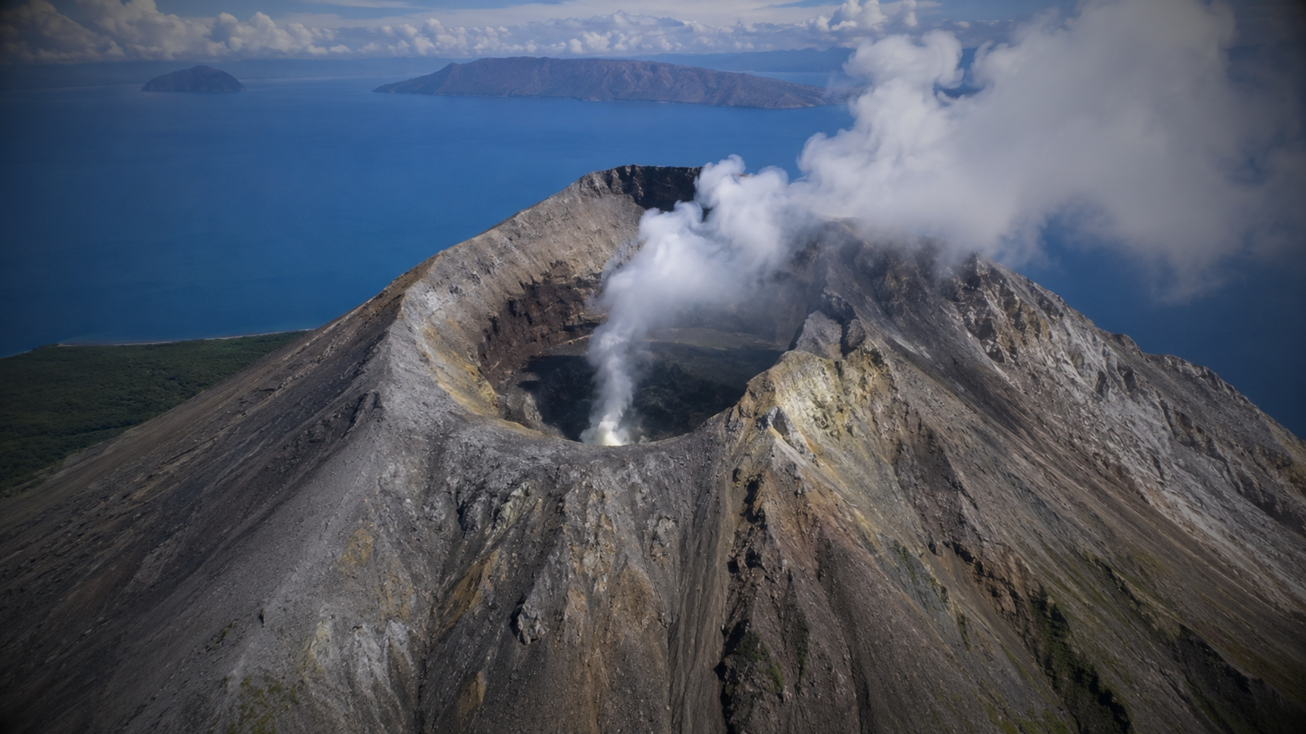 Ibu volcano and its broad truncated summit beneath an ash plume